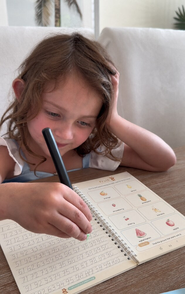 A girl rests her head on her hand while she traces numbers in a copybook