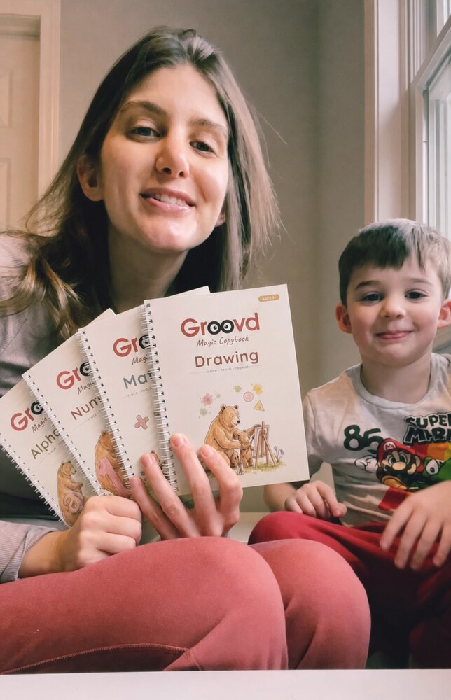 A mother holds the four Groovd copybooks while her son smiles beside her