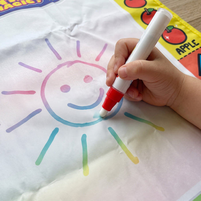 A child's hand draws a smiling sun on the mat with a water pen, the lines showing up in rainbow colors.