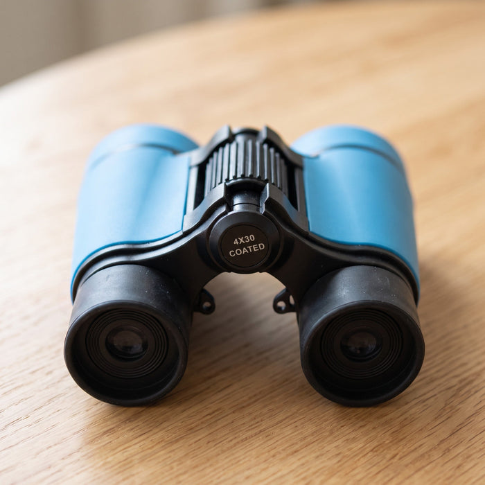 The binoculars seen from the end you look through, with the eye cups, the focus wheel and a label reading 4X30 coated