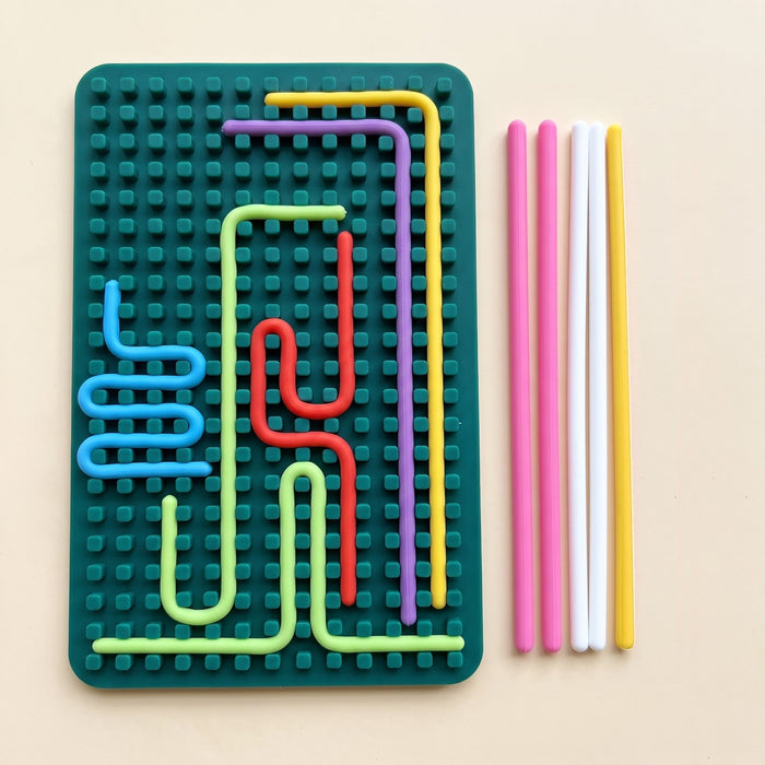 The peg side of the dark green board: colored strings wind between rows of small square pegs, with loose strings beside it