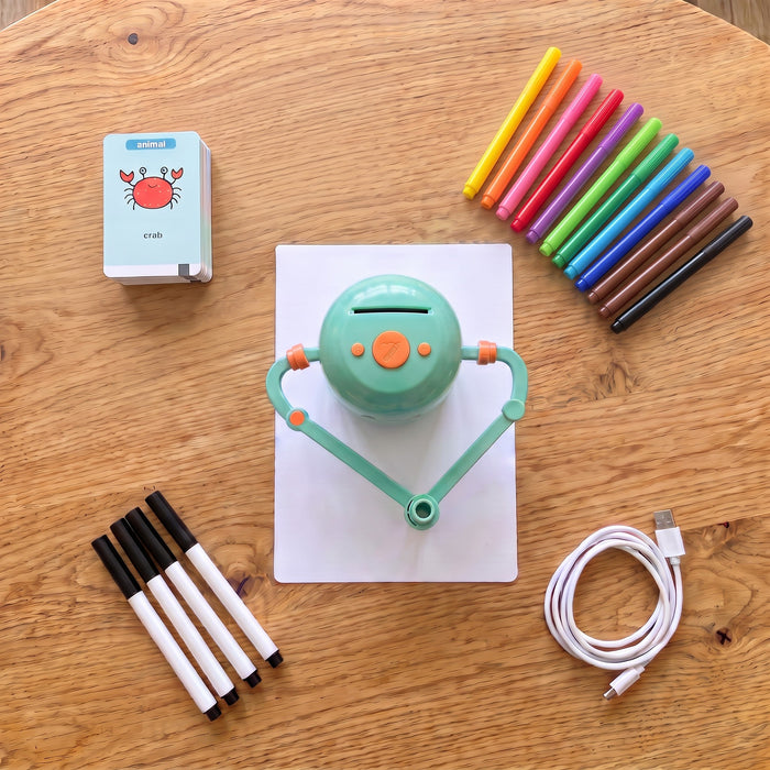 Contents laid out: the robot on a sheet of paper, a stack of picture cards, 12 coloured markers, 4 black pens and a USB cable