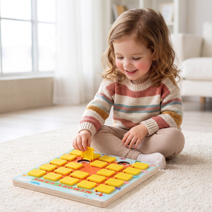 A smiling child sits on a soft rug and lifts one of the yellow flaps on the memory game board