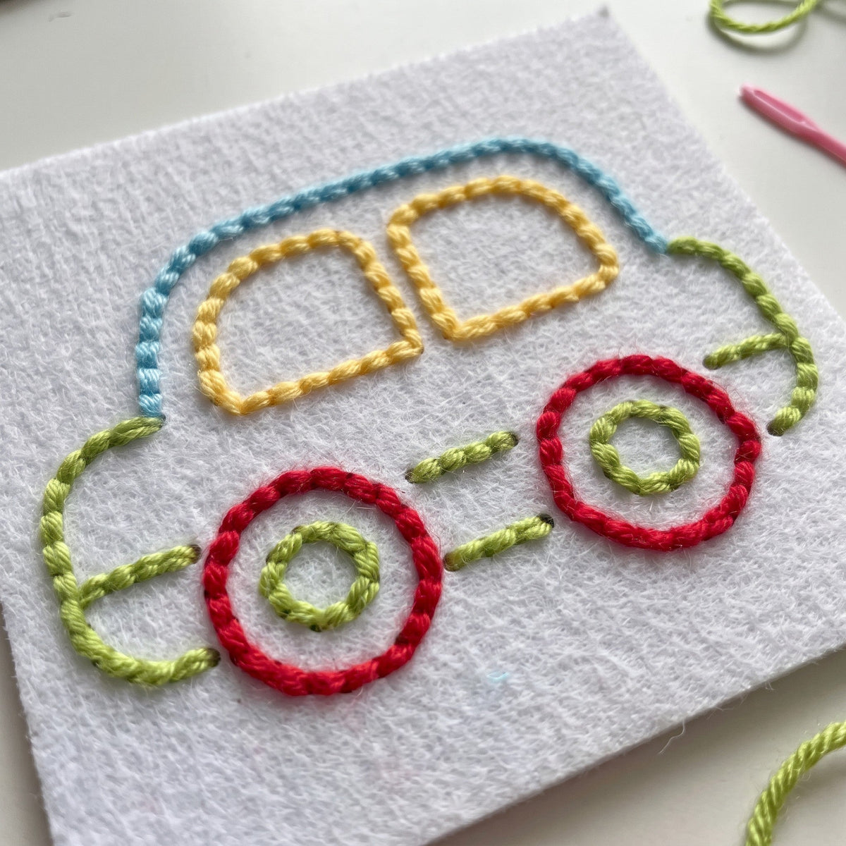 A finished car stitched on a felt card in blue, yellow, green and red thread